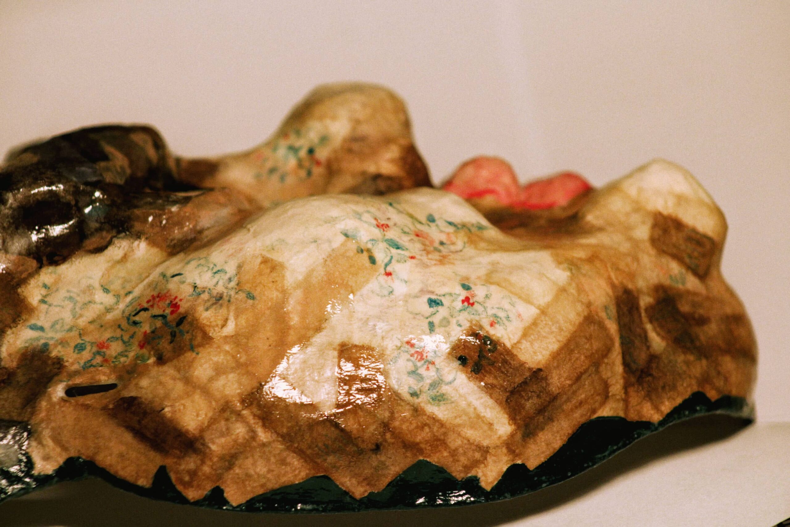 side view of handcrafted mask showing woven paper structure and floral embellishments