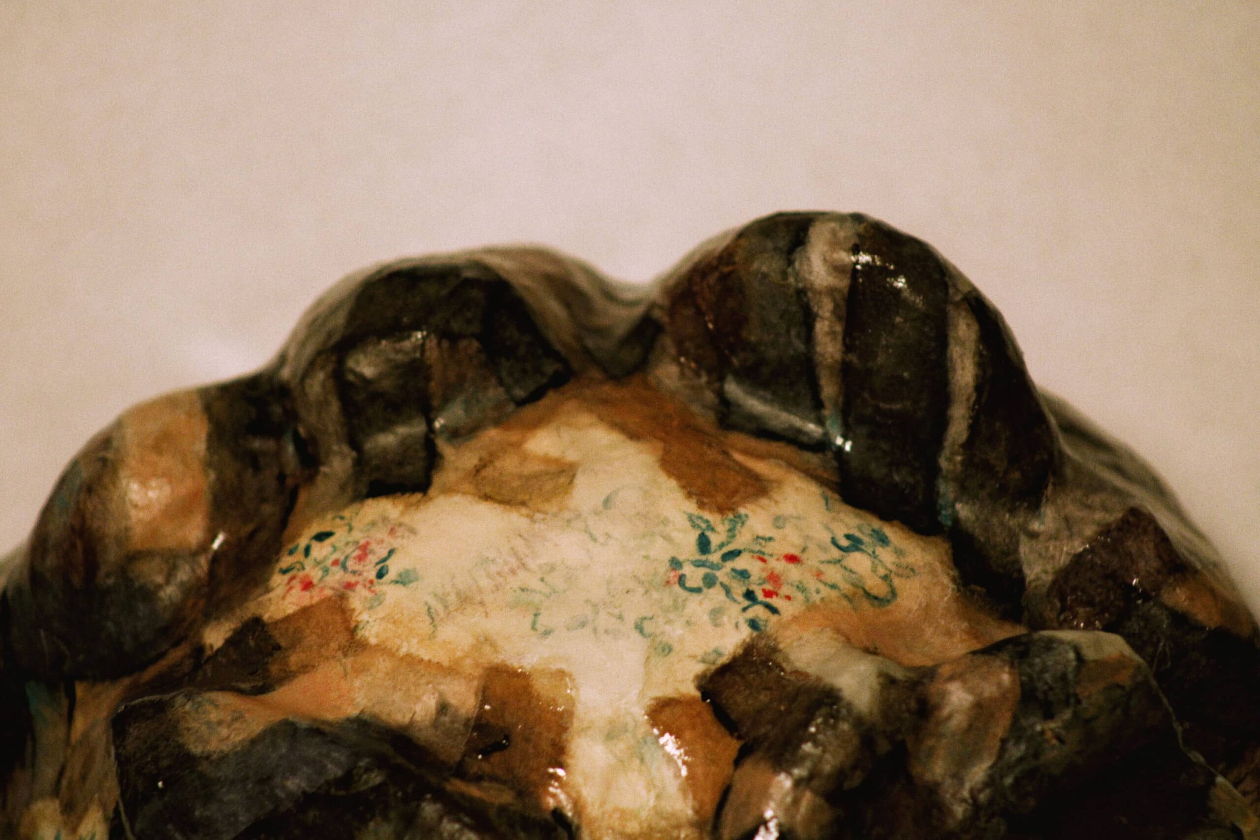 top of a cartoonish yakuza-inspired mask with thick brows, shellacked paper texture and floral motifs