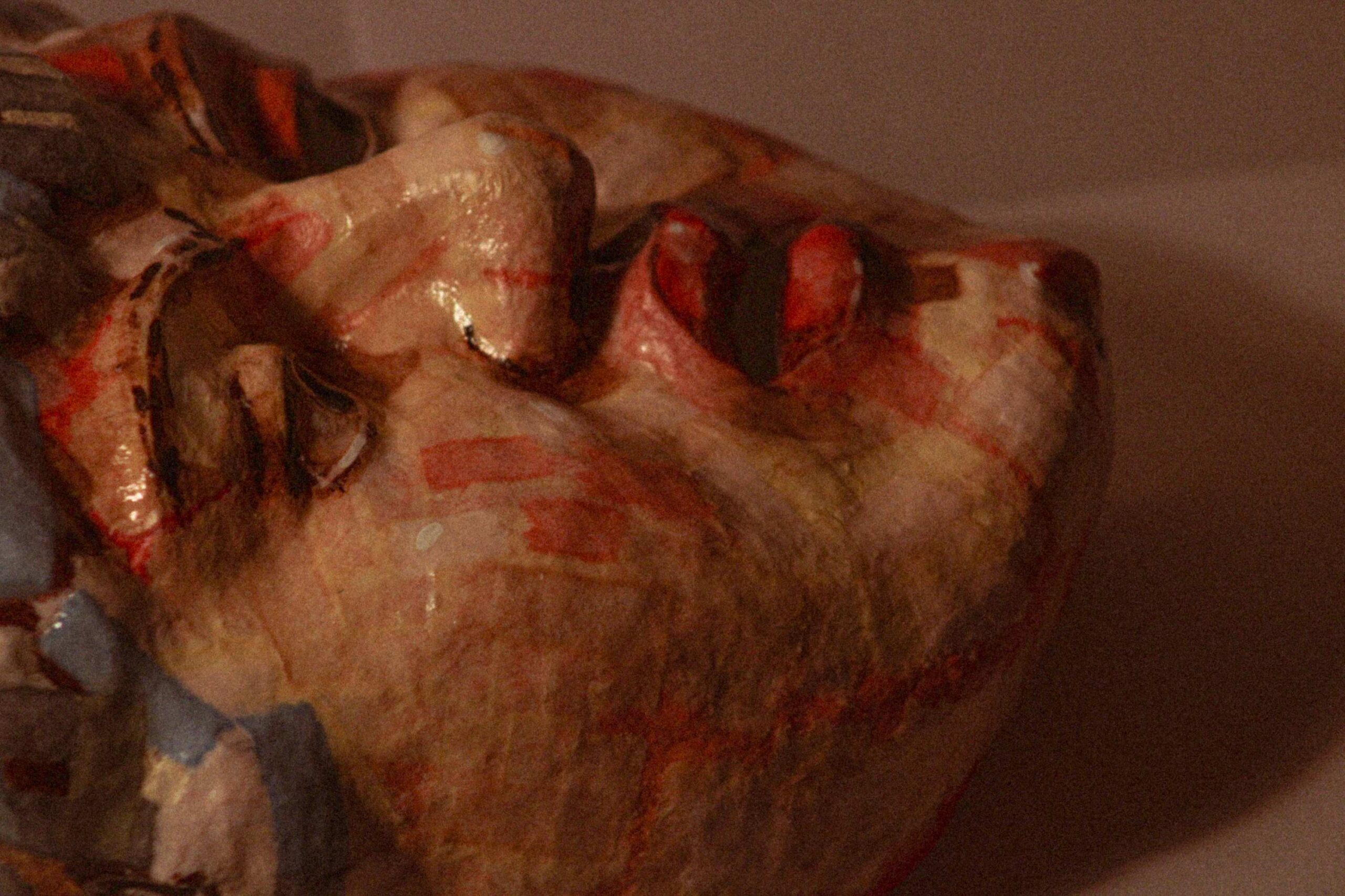 side view of the sculpted face in low light, highlighting the nose, lips, and uneven surface texture